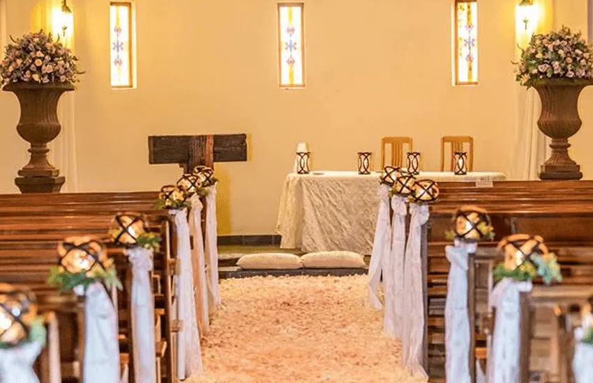 Wooden pews and floral urns at the altar of the Formal Chapel at Usambara Venue