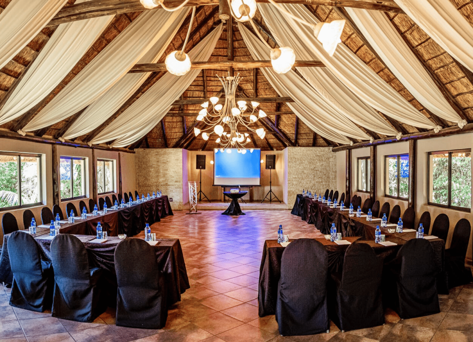 A thatched conference room set up with a projector screen at Usambara Venue
