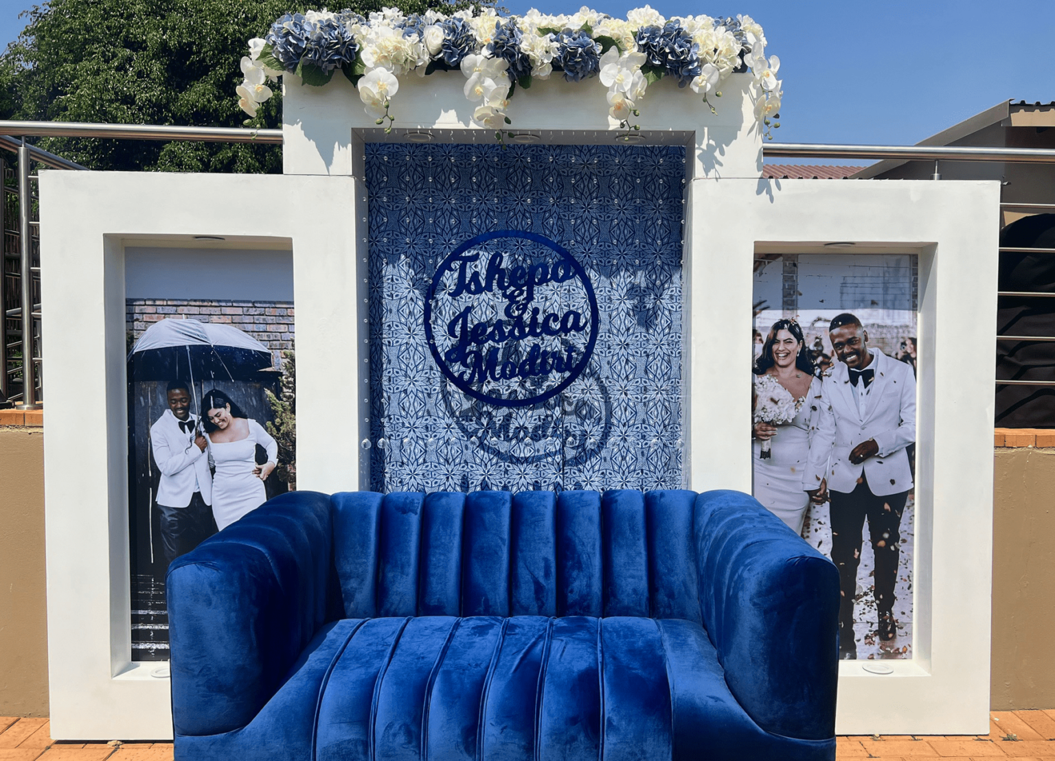 A blue velvet couch and personalised photo backdrop at Usambara Venue