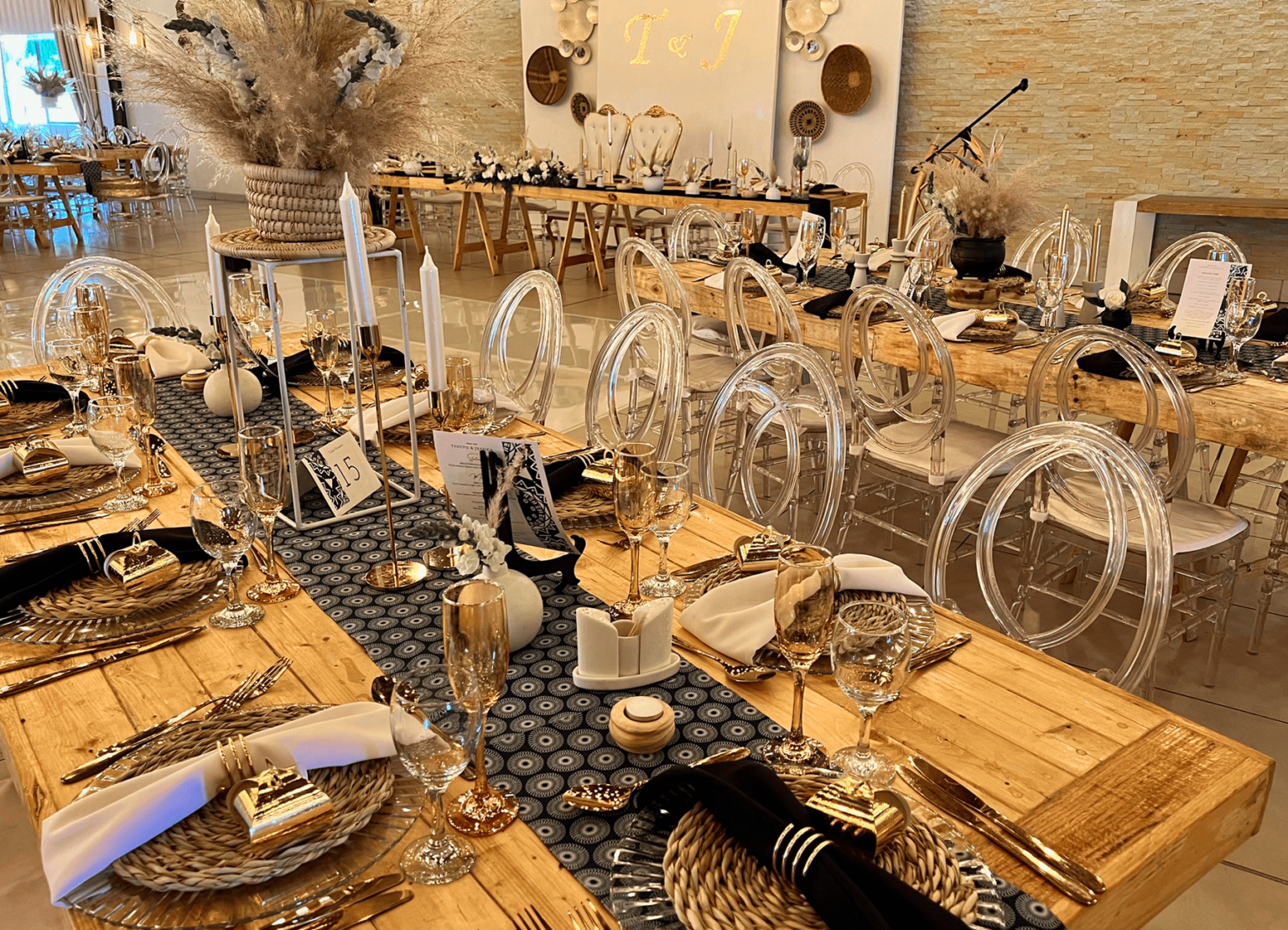Wooden banquet tables with dark runners and pampas grass at Usambara Venue