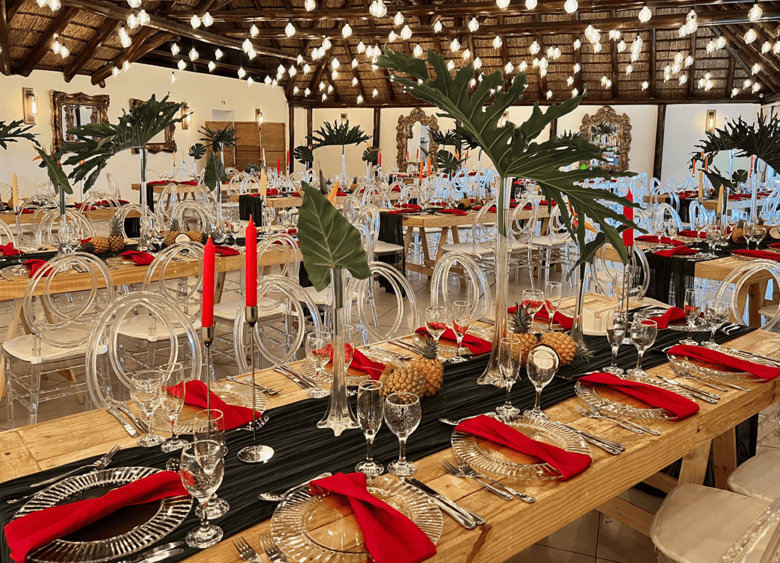 Banquet tables styled with red napkins and palm leaves at Usambara Venue