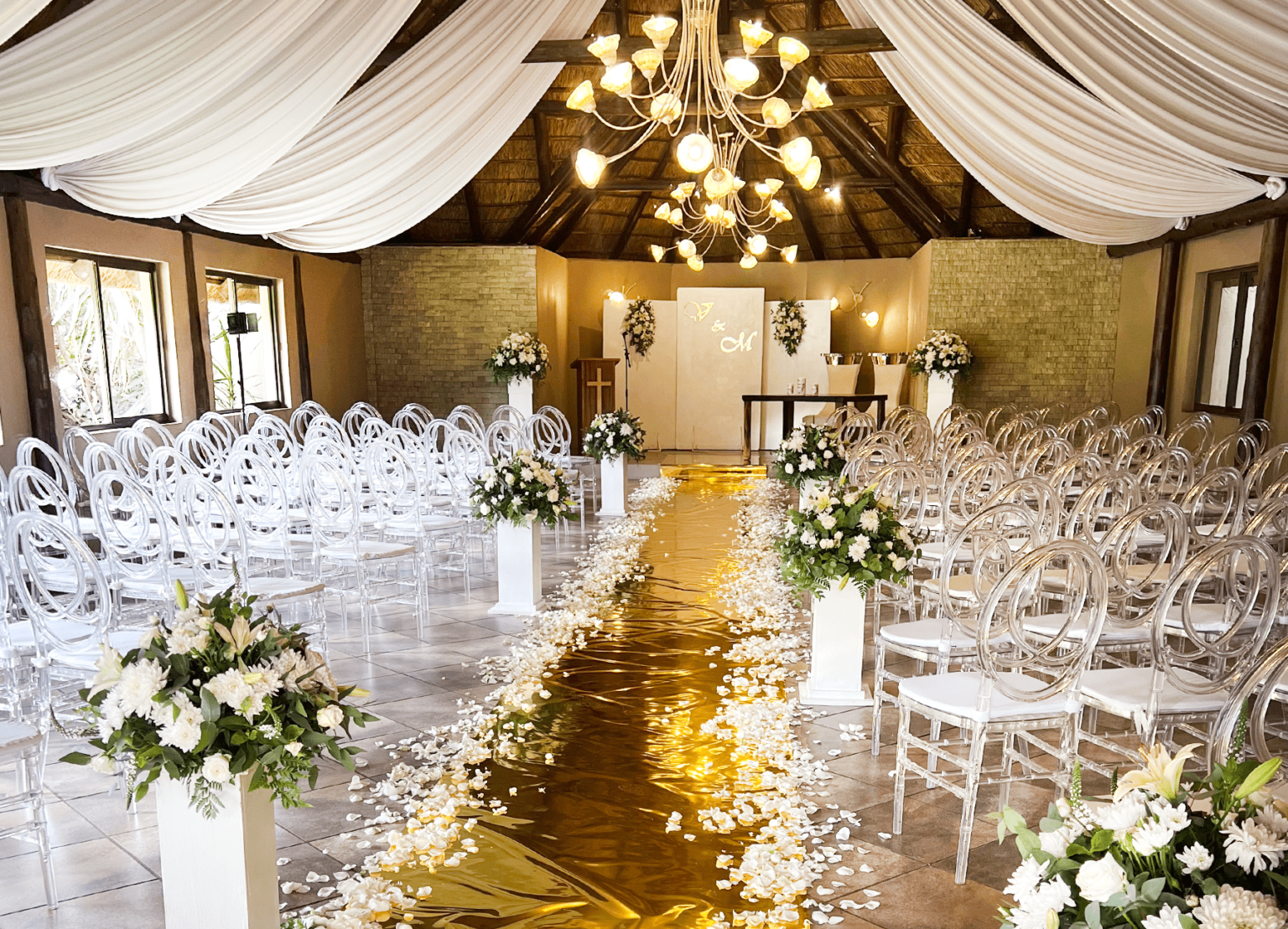 A chapel aisle dressed with a gold runner and white florals at Usambara Venue