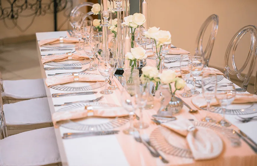 A long banquet table dressed with white roses in the Magali venue at Usambara Venue
