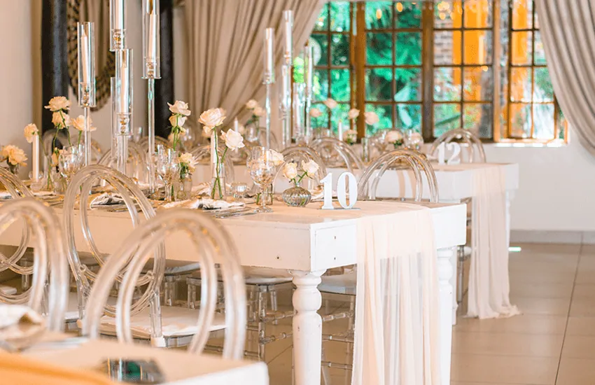 A candlelit table setting beside the arched windows of the Magali venue at Usambara Venue
