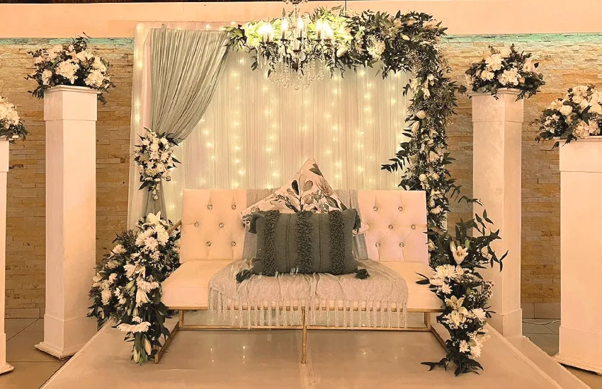 A bridal couch framed by a floral and drapery backdrop in the Mponde venue at Usambara Venue
