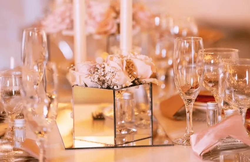 A mirrored centrepiece with blush flowers and champagne glasses at Usambara Venue