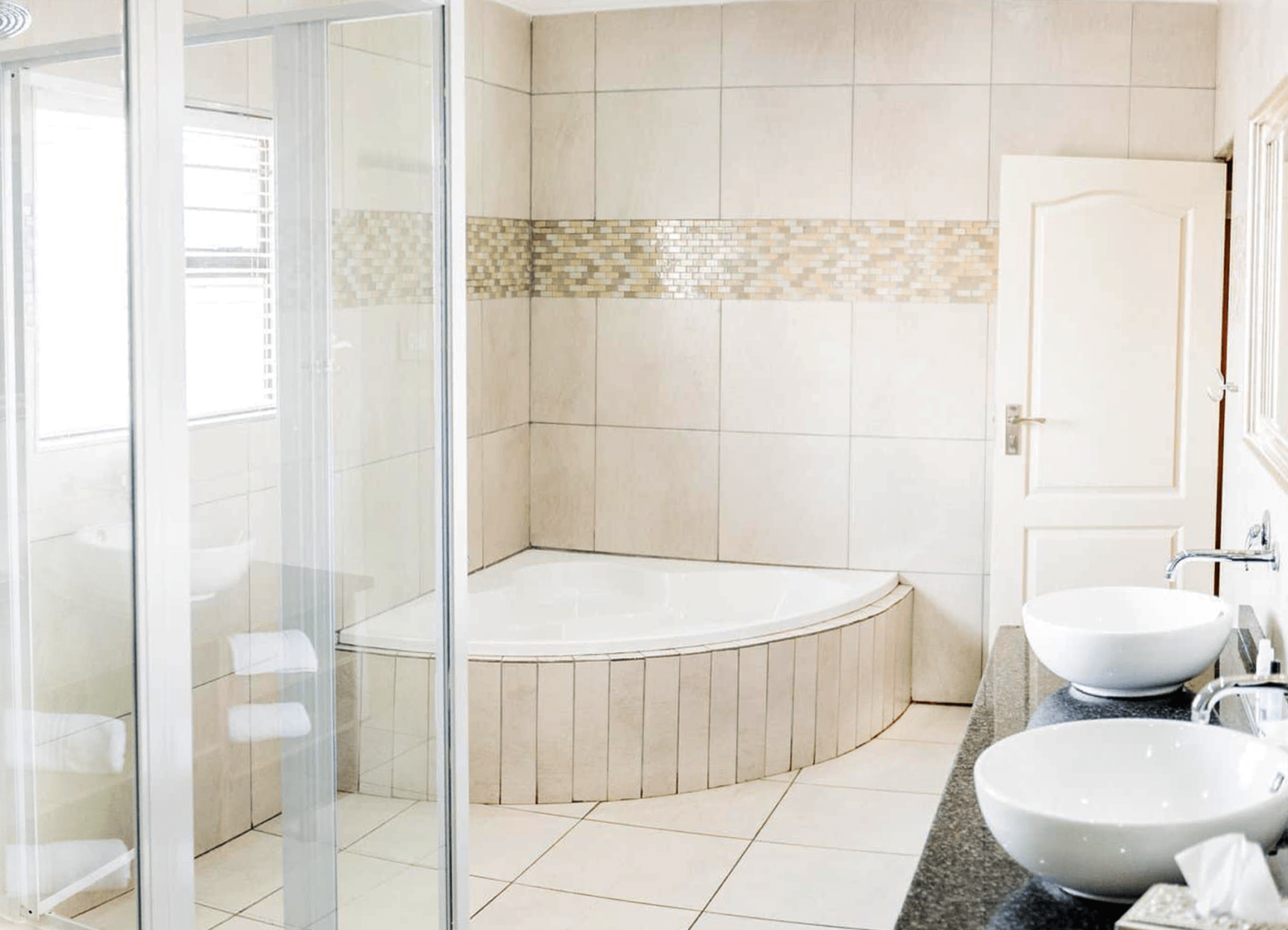 An en-suite bathroom with a corner bath at Usambara Lodge