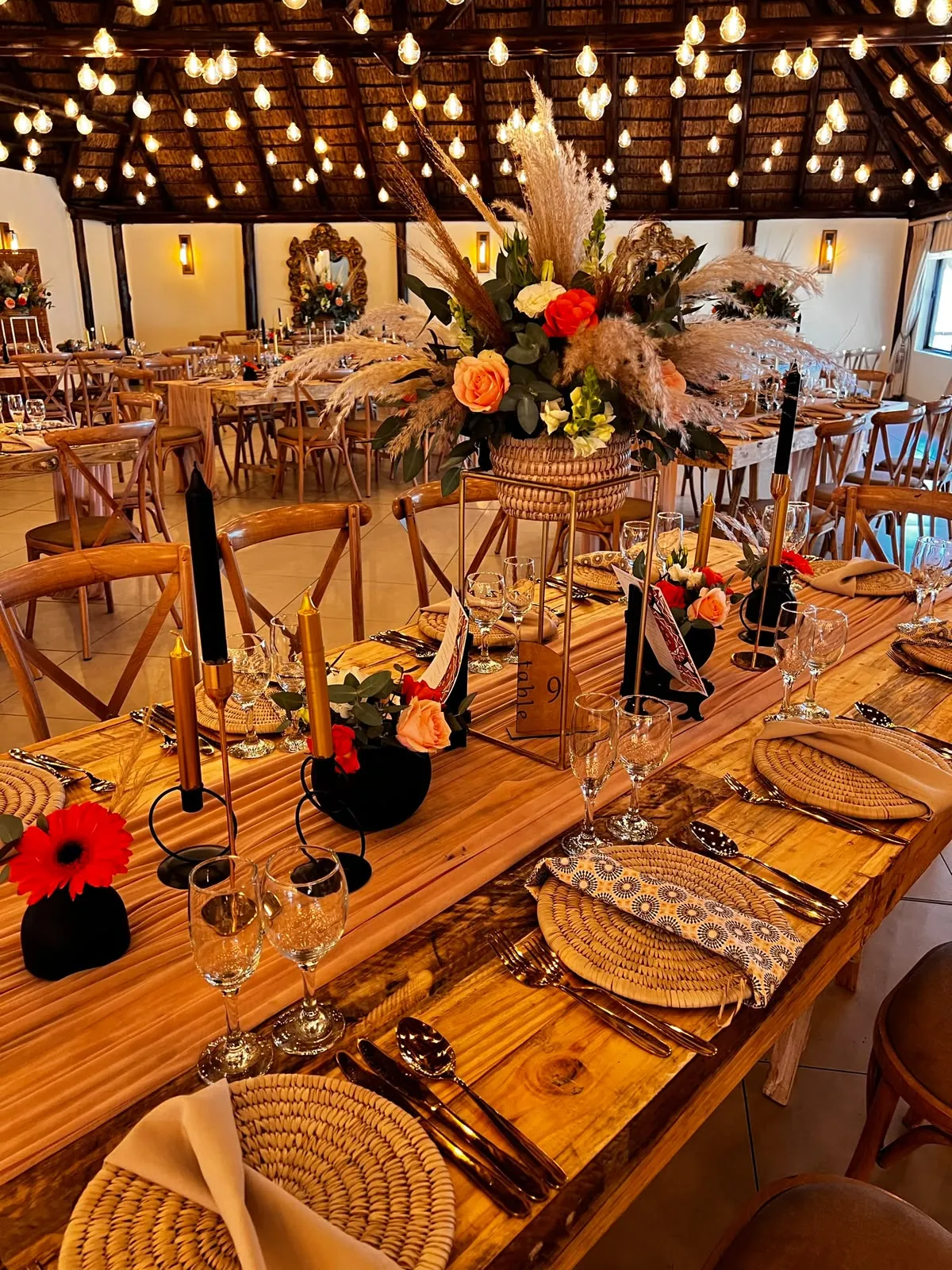 Wooden reception table with pampas grass, orange roses and black taper candles at Usambara Venue
